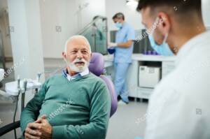 stock photo happy mature man and his dentist communicating during dental appointment at clinic 2075242690 e1712694655741